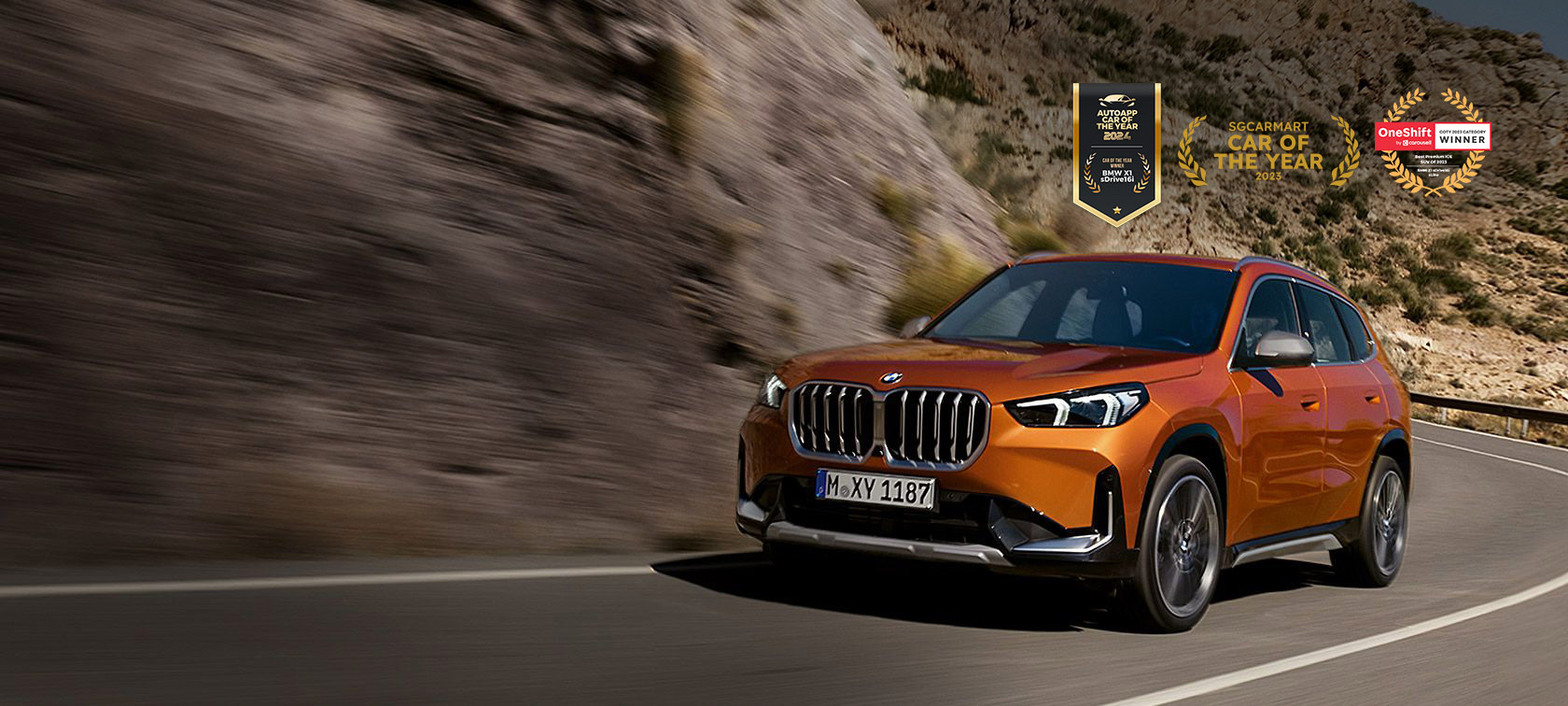 BMW X1 U11 xLine Utah orange metallic three quarter front view driving on country road